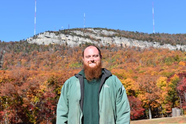 Man in front of mountain with green vest