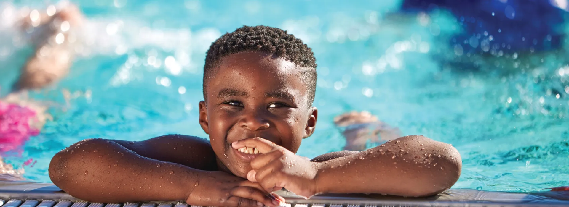 Boy smiling on the side of the pool